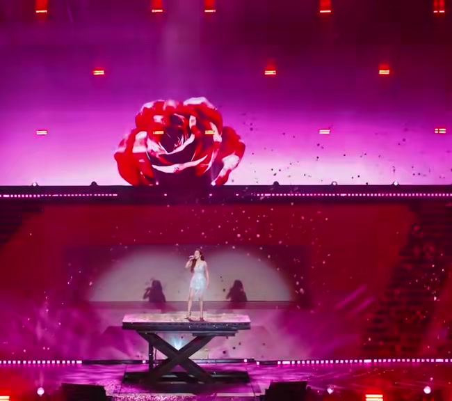 Bục nâng giữa sân khấu concert với màn LED hoa hồng đỏ khổng lồ phía sau trong mạch ballad