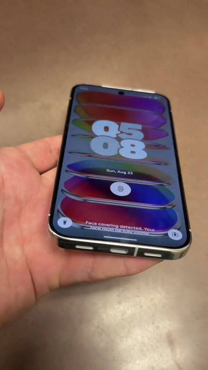 Tangan memegang Google Pixel 11 Pro XL dari depan dengan skrin berkunci menunjukkan tarikh
