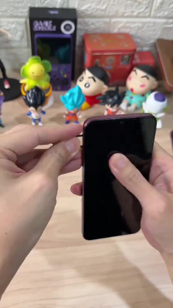 Infinix Smart 20e warna Deep Cherry dipegang dari sisi menunjukkan badan phone dan skrin hitam