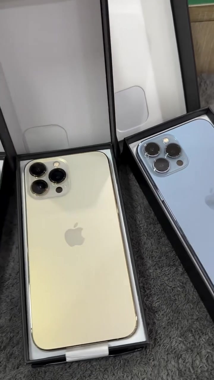 Dua unit iPhone dalam kotak terbuka, satu warna emas satu biru, dilihat dari bahagian belakang