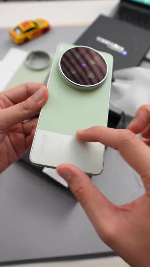 Dua tangan memegang vivo X300 Ultra warna hijau pudar menunjukkan modul kamera bulat di belakang