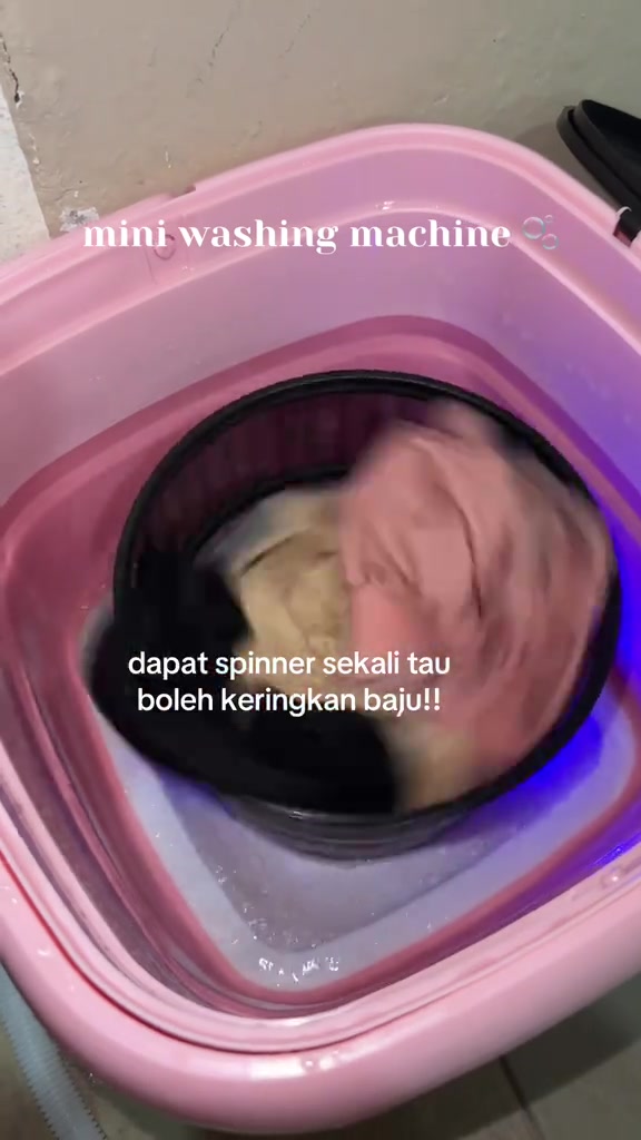 Bakul spinner hitam berputar di dalam mesin basuh mini lipat merah jambu untuk peras air baju