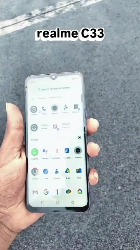Tangan memegang Realme C33 menunjukkan skrin utama dengan deretan ikon aplikasi