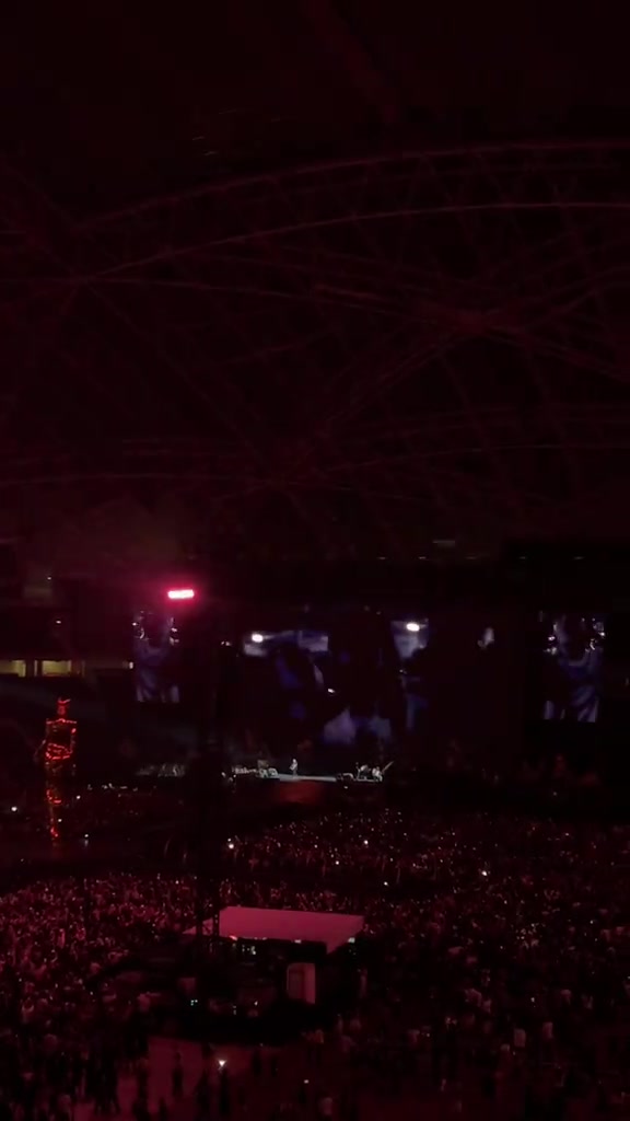 Khán đài và mái vòm sân vận động National Stadium Singapore nhìn từ tầng cao trong ánh đèn đỏ, bên dưới là biển khán giả cầm đèn điện thoại