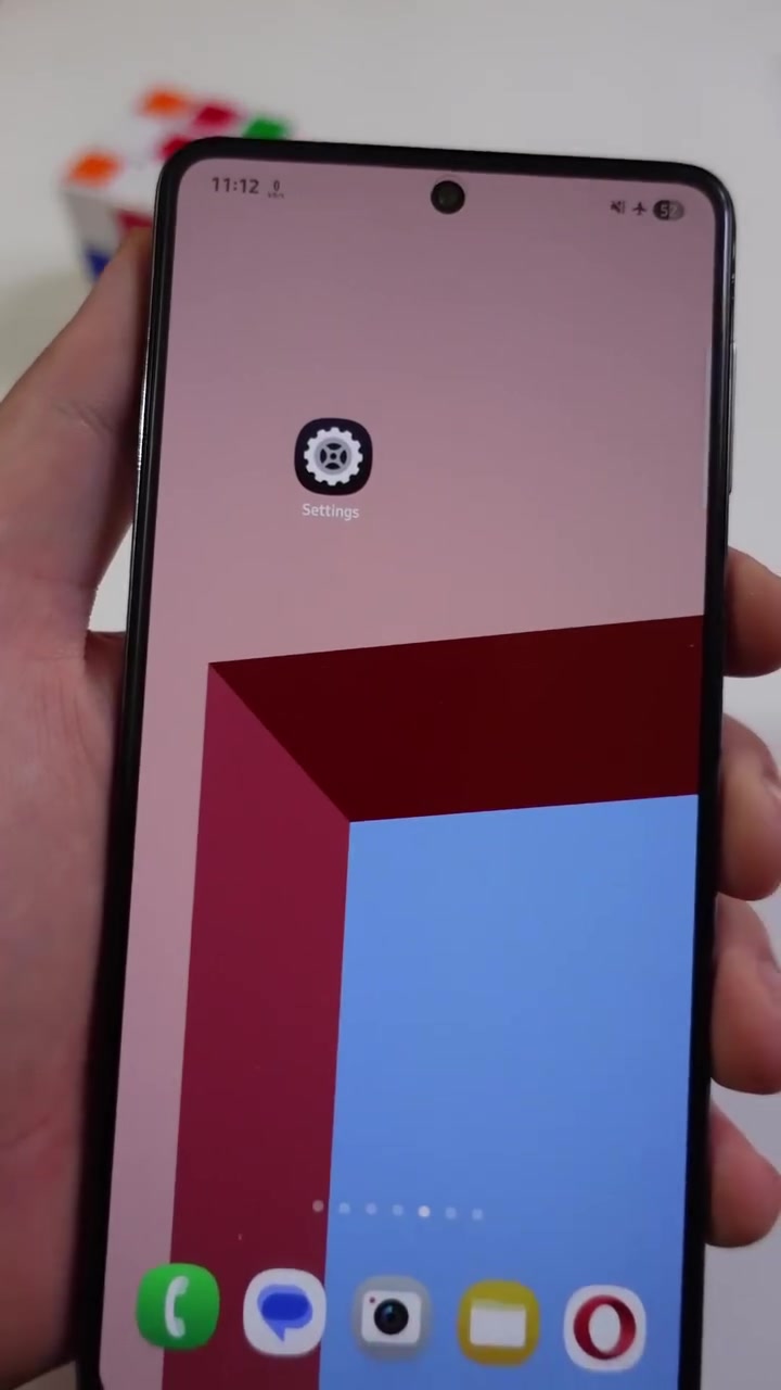 Skrin utama phone Android dengan ikon Settings kelihatan jelas di tengah skrin
