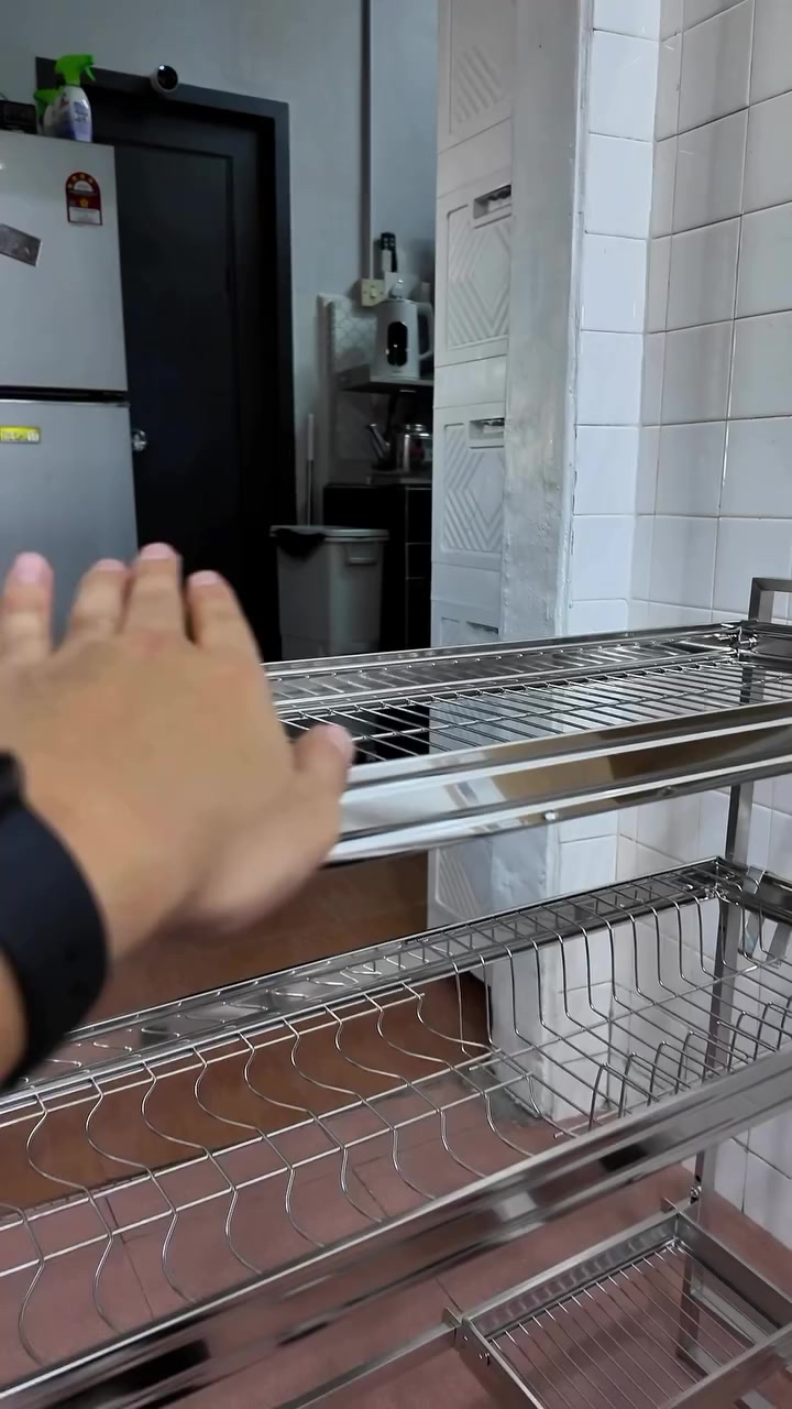 Tangan menyentuh permukaan rak pinggan stainless steel atas sinki dua tingkat