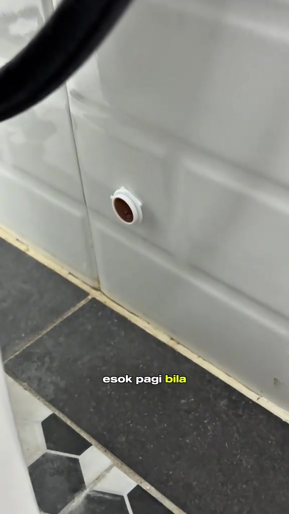 Stasiun umpan lipas kecil berwarna putih ditampal pada dinding jubin bilik air berhampiran mangkuk tandas