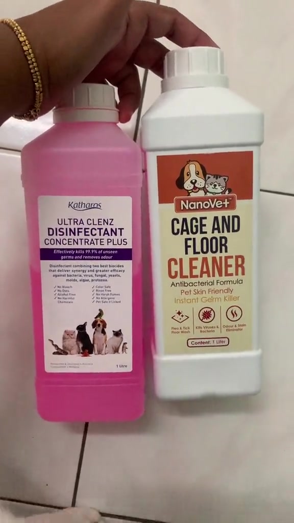 Dua botol pencuci lantai selamat haiwan peliharaan dipegang di atas lantai jubin