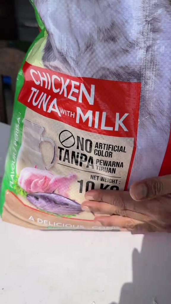 Tangan memegang beg kibbles 10 kilogram perisa chicken tuna with milk dengan label tanpa pewarna tiruan