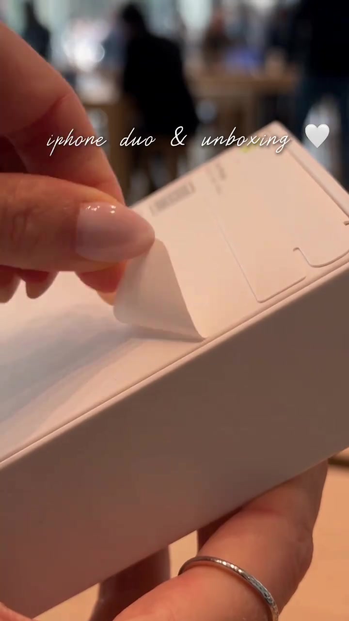 Tangan mengoyak seal kotak iPhone Duo di dalam Apple Store