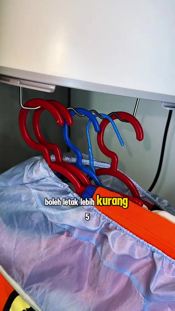 Barisan penyangkut baju merah dan biru disangkut dalam beg mesin pengering portable, muat sekitar lima helai