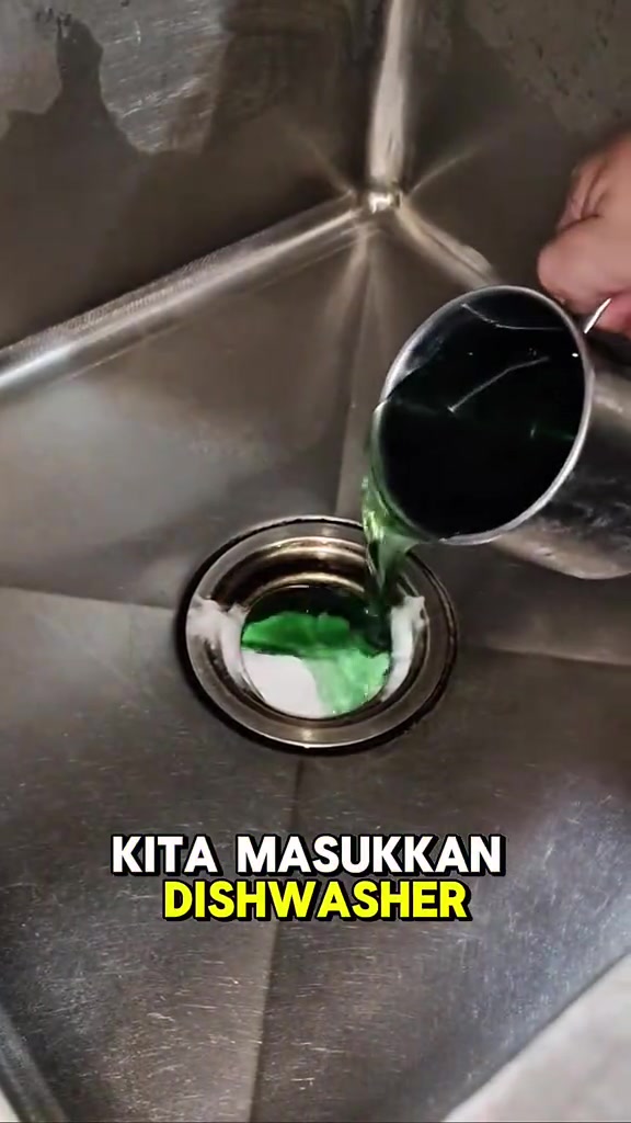 Cawan keloli menuang cecair pencuci pinggan hijau ke dalam lubang sinki stainless yang berisi serbuk putih