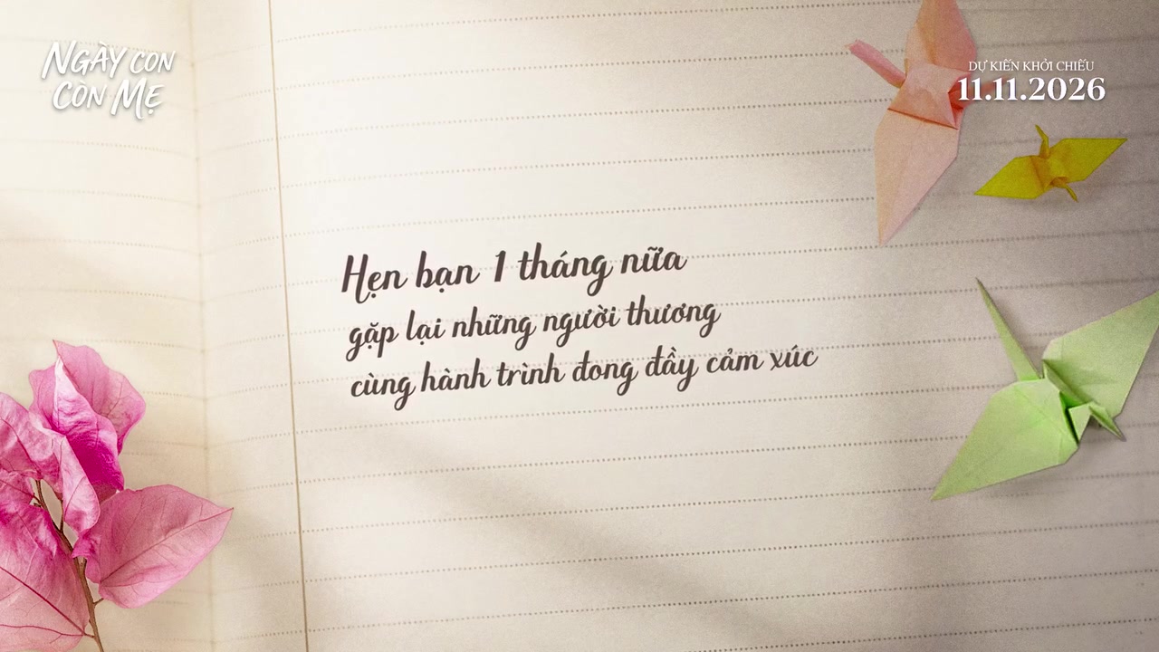 Khung giấy kẻ ngang chốt hậu trường phim Ngày Con Còn Mẹ với dòng chữ viết tay hẹn gặp lại sau 1 tháng nữa, xung quanh là hạc giấy và cánh hoa giấy hồng