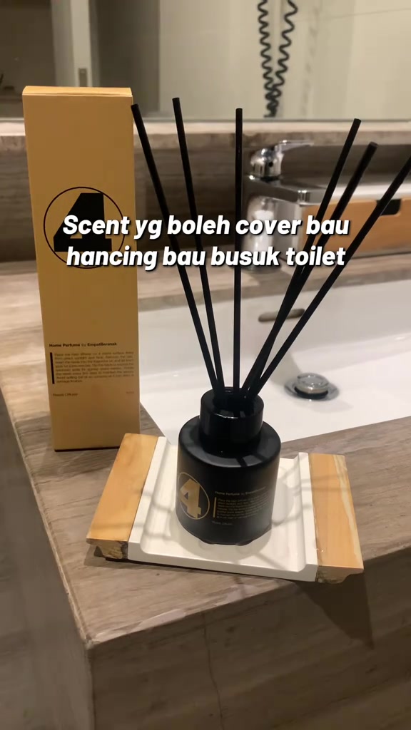 Botol reed diffuser hitam dengan stick hitam diletak atas sinki bilik air sebelah kotak pembungkusan