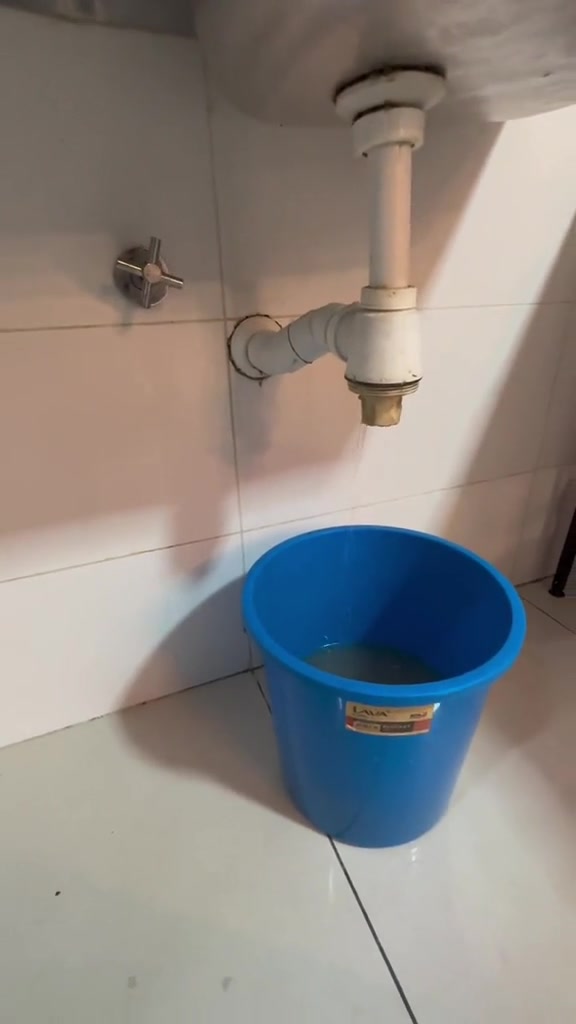 Paip putih bawah sinki sudah dibuka dengan baldi biru diletakkan di bawahnya untuk tadah air