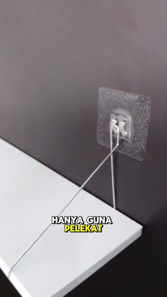 Patch pelekat lutsinar dengan cangkuk wayar memegang papan rak putih di dinding berwarna gelap