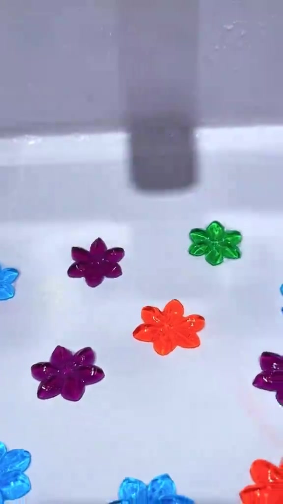Gel stamp pewangi tandas berbentuk bunga warna-warni melekat pada permukaan seramik putih