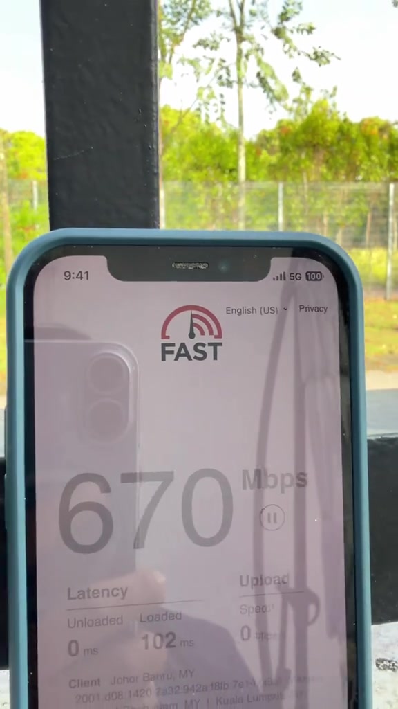 Skrin ujian kelajuan FAST pada iPhone menunjukkan 670Mbps semasa ujian dengan ikon 5G dan lokasi klien Johor Bahru, Malaysia.