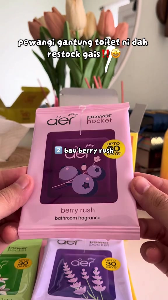 Pek pewangi gantung Godrej Aer Power Pocket bau berry rush dipegang di tangan dengan pek lain di bawah