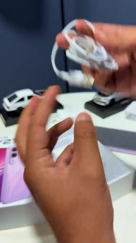 Tangan memegang kabel dan pengecas putih yang dikeluarkan dari kotak vivo Y21d