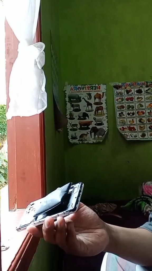 Telefon terbuka dengan bateri hitam yang kembung menonjol keluar dari rangka
