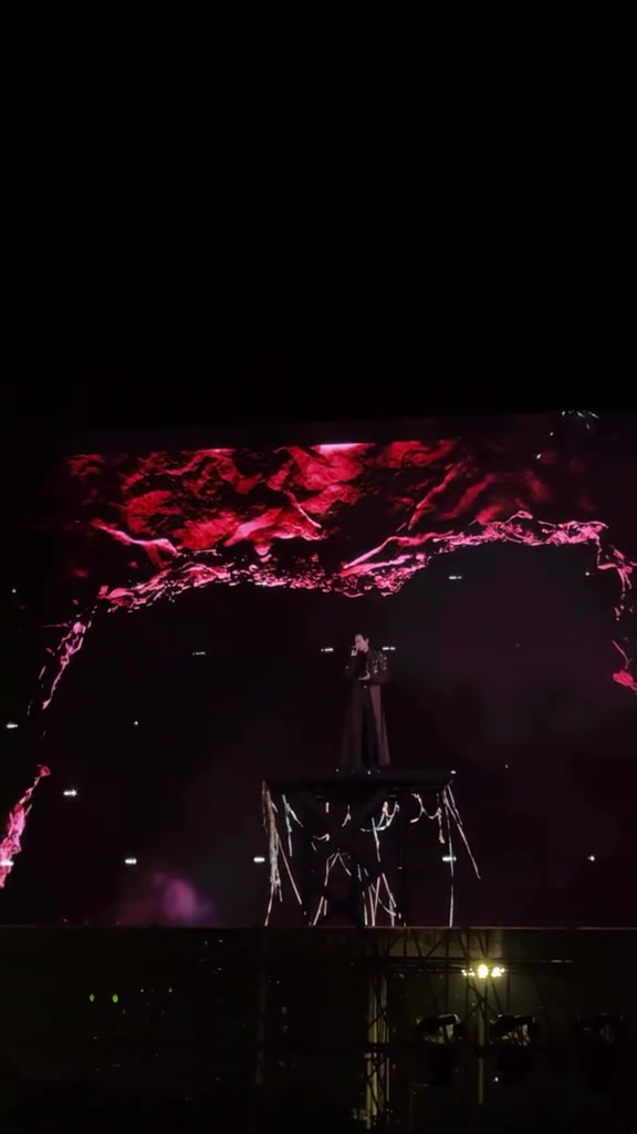 Toàn cảnh sân khấu concert Anh Trai Vượt Ngàn Chông Gai 2026 với bục nâng ở trung tâm và màn LED vân đỏ phía sau trong tiết mục Nhức Tiềm Thức