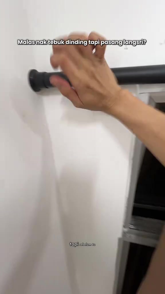 Tangan memulas hujung rod tension hitam yang menekan pada dinding putih sebelah tingkap
