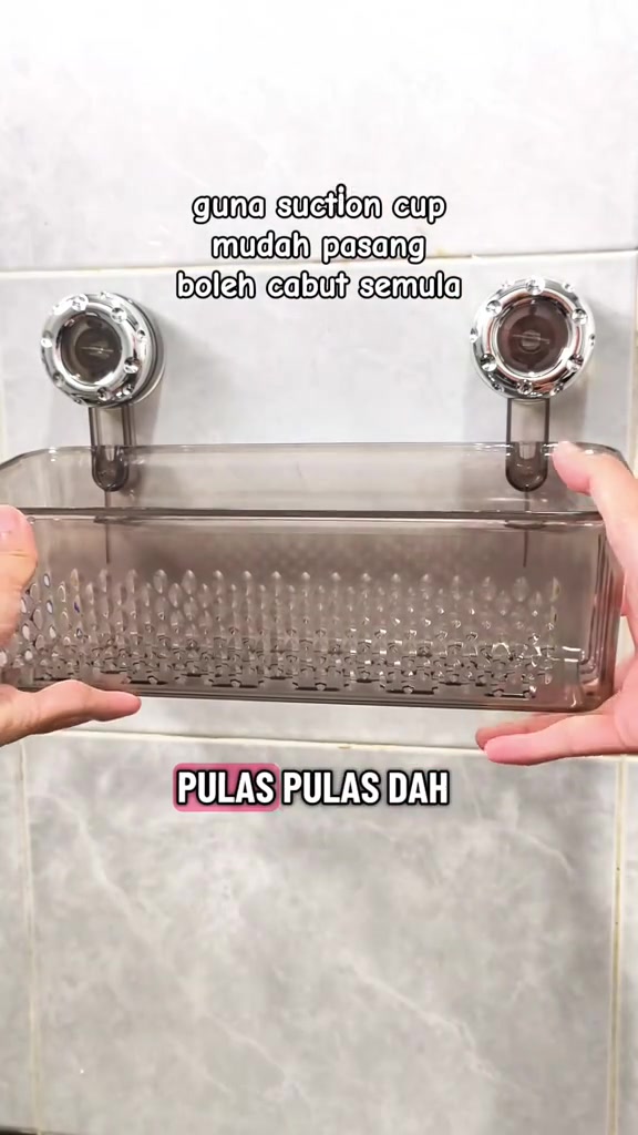 Dua tangan memasang rak cawan sedut kelabu pada dinding jubin sambil memulas kunci sedutan