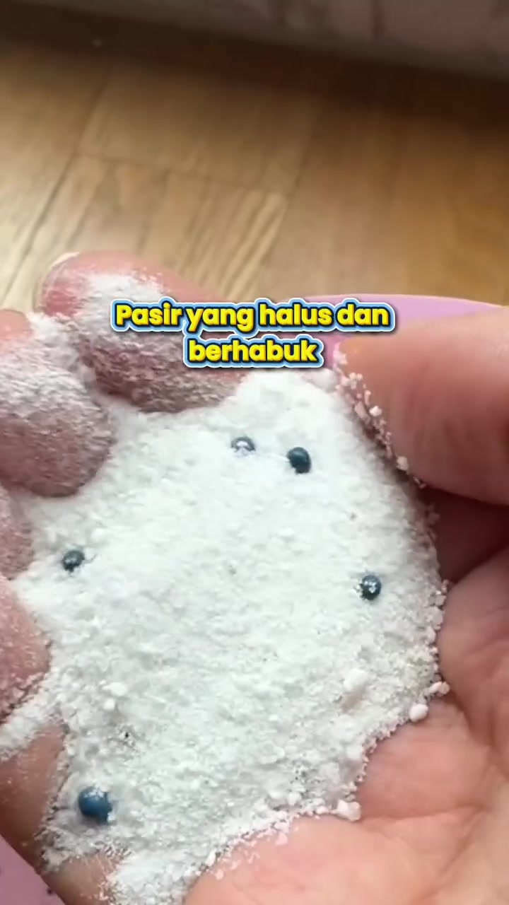 Tangan memegang pasir kucing putih yang halus dan berhabuk