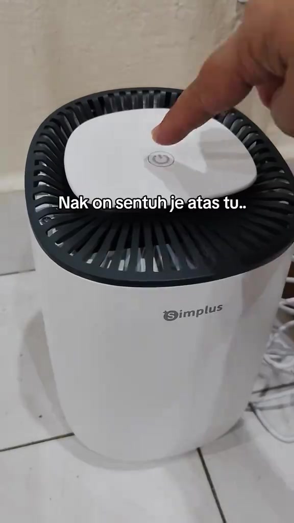 Jari menekan butang sentuh di bahagian atas dehumidifier Simplus berwarna putih
