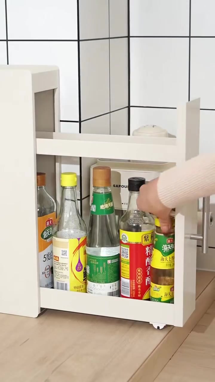 Rak pull-out sempit berwarna putih berisi botol kicap dan cuka, tangan mencapai botol
