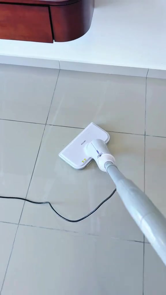 Kepala steam mop putih di atas lantai jubin putih bersih dengan wayar hitam terjuntai di sebelah