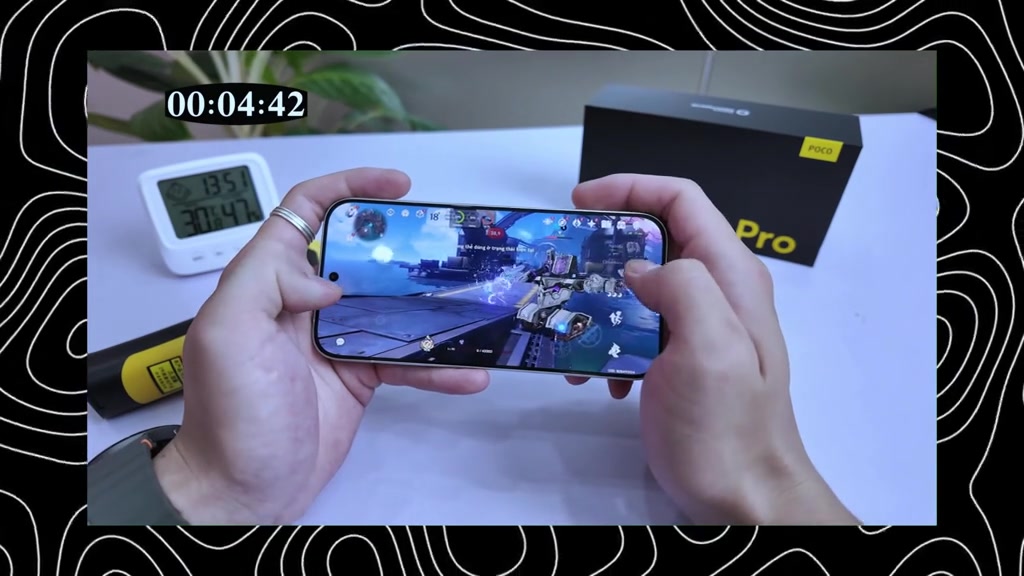 Hai tay cầm ngang POCO X8 Pro đang chơi game, bên cạnh là đồng hồ bấm giờ và hộp máy màu đen