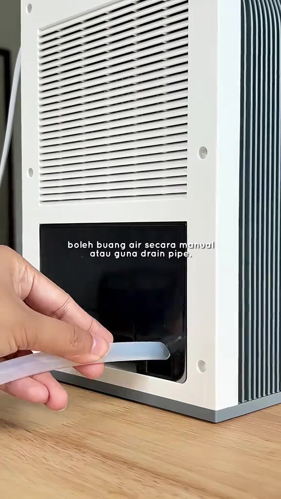 Tangan memasang tiub drain lut sinar pada bahagian belakang dehumidifier Gaabor untuk buang air berterusan