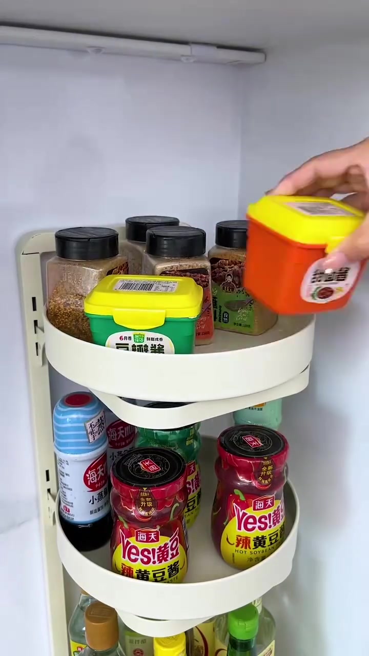 Rak sudut tiga tingkat dengan tray bulat boleh pusing berisi botol sos dan bekas perasa, tangan menyusun bekas
