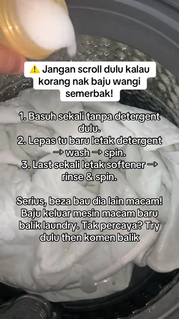 Tangan menuang detergen ke dalam dram mesin basuh berisi baju putih