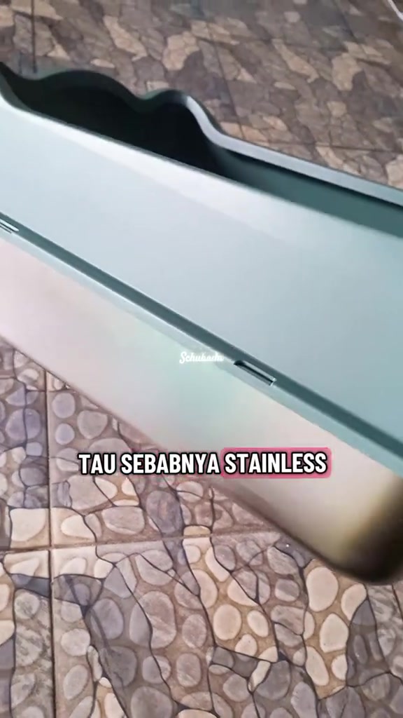 Sisi penutup litter box berwarna hijau gelap dipasang rapat pada dulang stainless steel di lantai berjubin