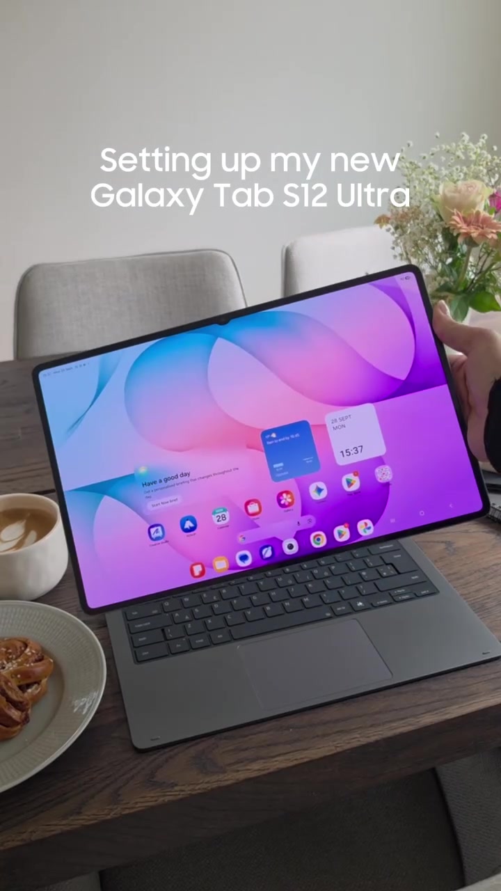 Galaxy Tab S12 Ultra dipasang pada keyboard cover di atas meja kayu bersama cawan kopi, gaya penggunaan seperti laptop