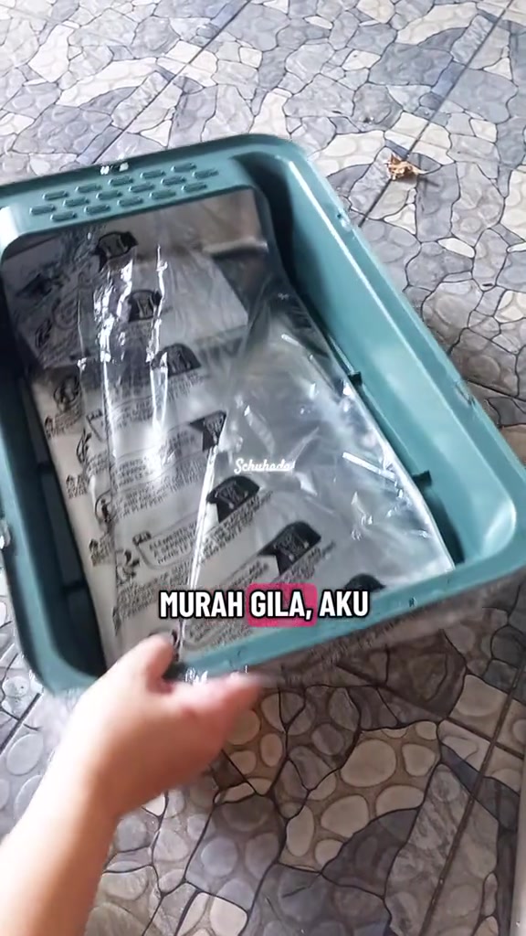 Bekas litter box stainless steel masih berbalut plastik di dalam bingkai hijau sedang dibuka keluar dari kotak penghantaran