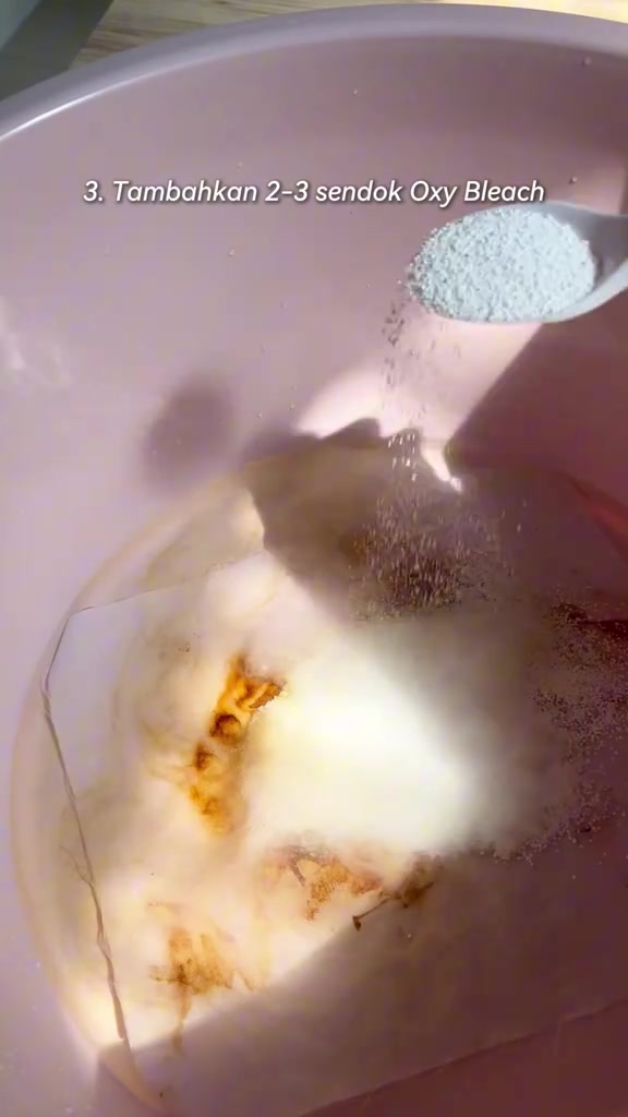 Sudu menuang serbuk oxygen bleach ke dalam besen berisi air dan kain putih berkesan kuning