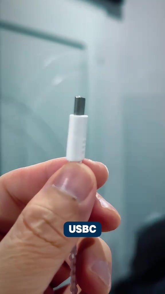 Hujung penyambung USB-C earphone berwayar putih dipegang antara dua jari