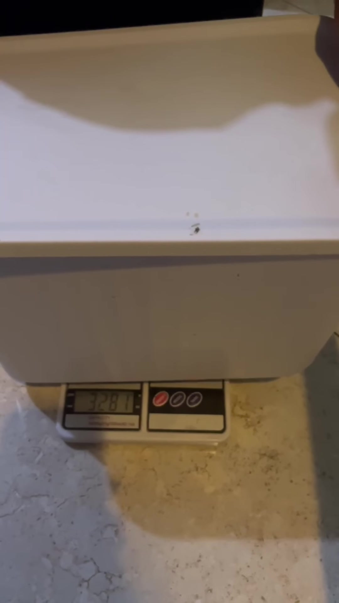 Bekas plastik putih diletak atas penimbang dapur dengan bacaan 3.281, cara timbang kucing tanpa perlu dukung