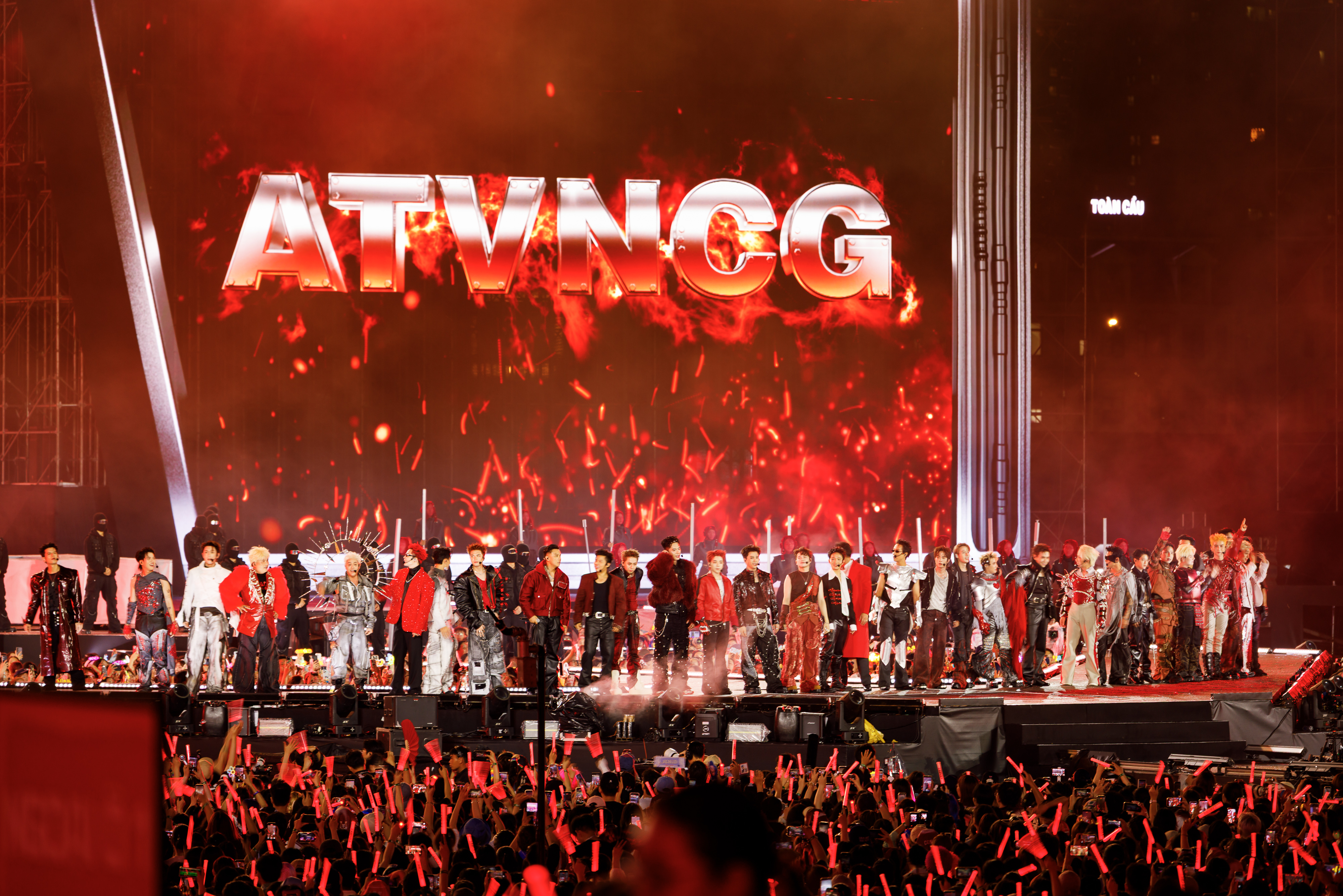 Hàng chục Anh Tài đứng thành hàng trên sân khấu chính concert Anh Trai Vượt Ngàn Chông Gai 2026, phía sau là chữ ATVNCG rực đỏ trên màn LED lớn, phía trước là biển lightstick của khán giả