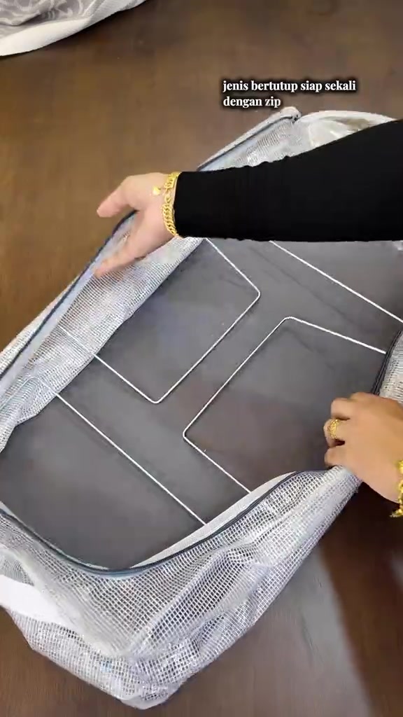Tangan membuka zip organizer fabrik kelabu dengan rangka wayar kelihatan di dalamnya