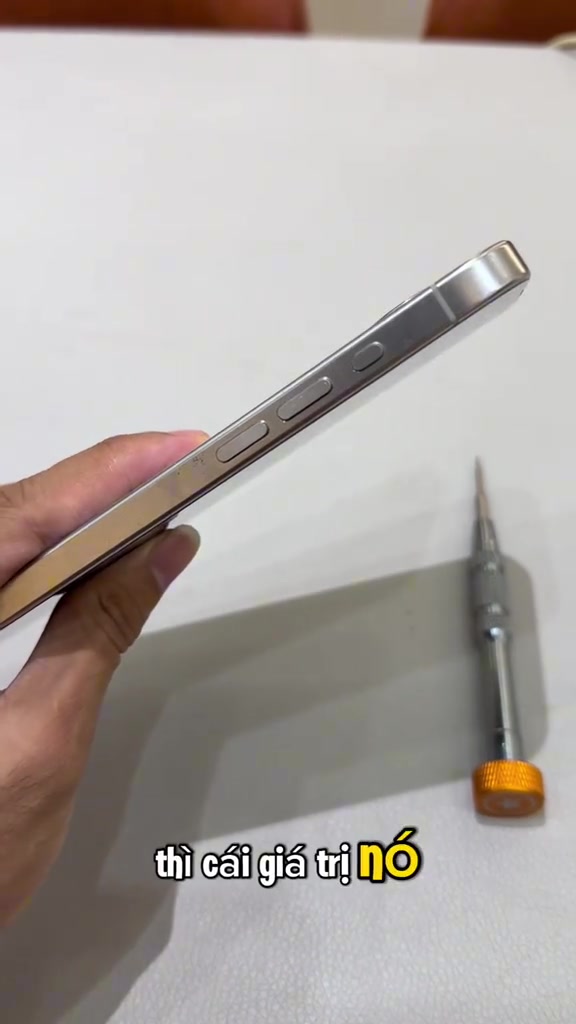 Cạnh sườn iPhone đặt trên bàn cạnh một cây tua vít sửa chữa đầu màu cam