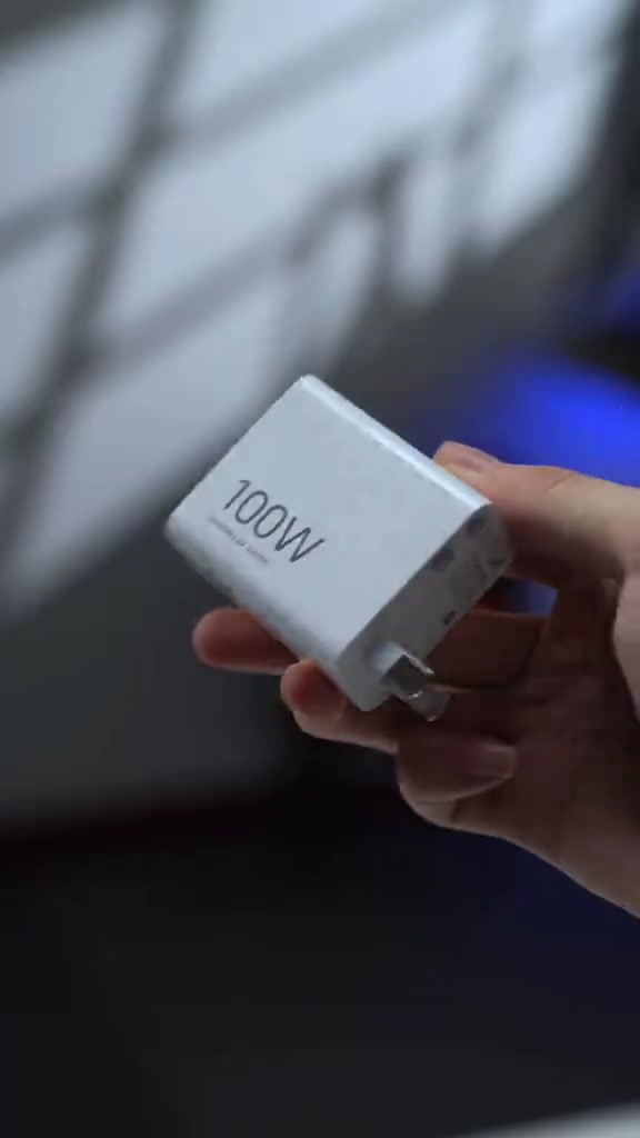 Charger putih bertulis 100W yang disertakan dalam kotak Xiaomi 18 Pro, dipegang pada tangan