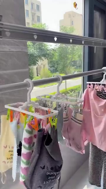 Beberapa hanger berklip tergantung pada rail dengan stokin dan baju kecil tersepit kemas