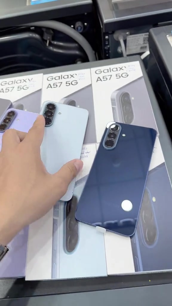 Ba chiếc Galaxy A57 5G màu tím ngọc, xanh nhạt và xanh navy đặt trên hộp sản phẩm