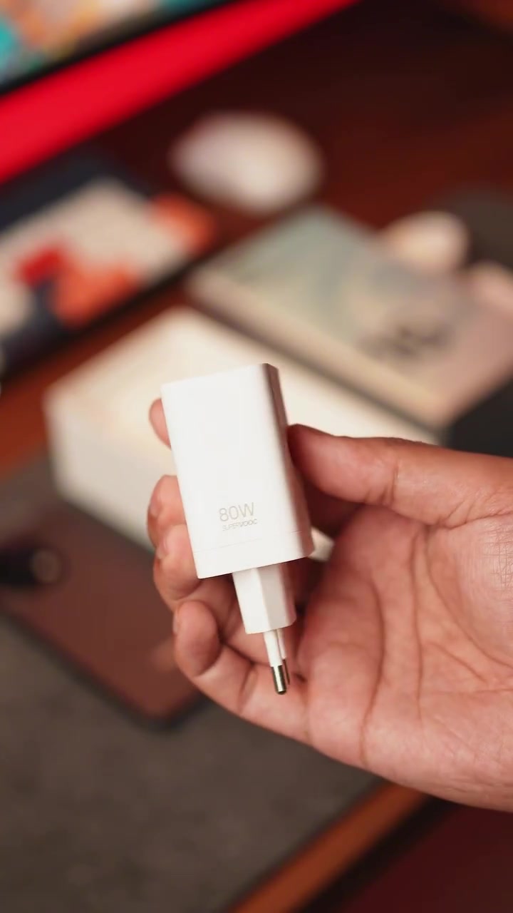 Pengecas putih OPPO 80W SUPERVOOC dipegang satu tangan dengan kepala plug dua pin kelihatan jelas