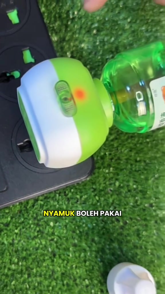 Vaporizer ubat nyamuk elektrik hijau putih dengan lampu penunjuk dipasang pada papan sambungan bersama botol refill cecair hijau